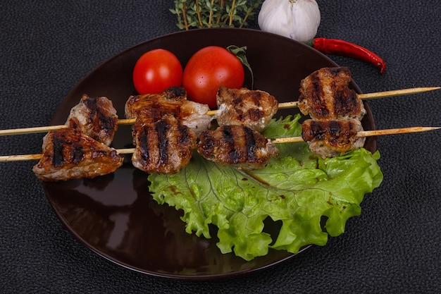 Pork kebab skewers in the plate with salad leaves and tomatoes