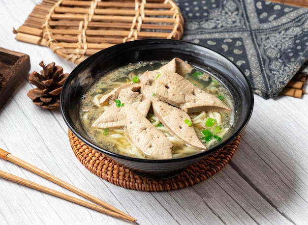 Pork liver noodle soup in a dish isolated on wood table side view taiwan food