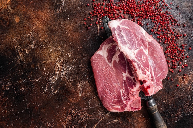 Pork loin steak from raw neck fillet meat on butcher knife Dark background Top view Copy space