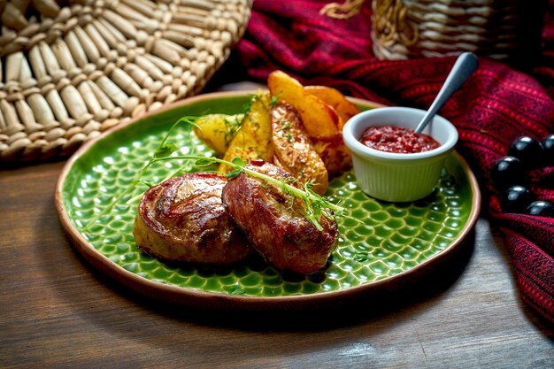 Pork medallions with a side dish of potatoes in a green plate Pork steak on a wooden background