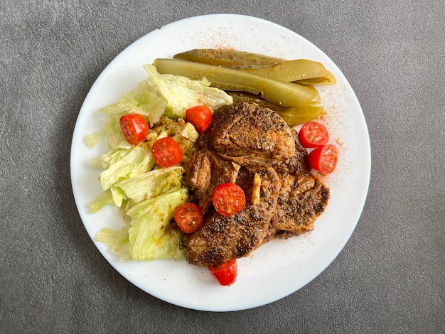 Pork neck in its own sauce with pickled cucumber and iceberg lettuce and tomatoes