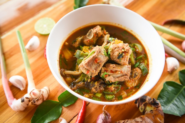 Pork rib curry spicy soup  pork bone with hot and sour soup bowl with fresh vegetables Tom Yum thai herbs and spices ingredients.