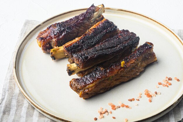 Pork ribs grilled with BBQ sauce and caramelized in honey set, on plate, on white stone  background