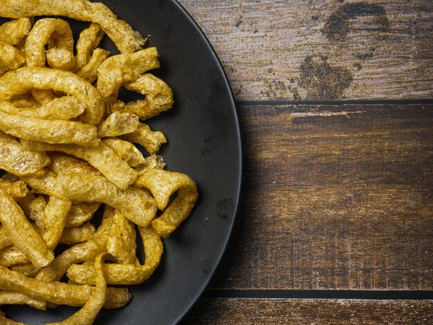 Pork rind in black plate on wood table for food concept