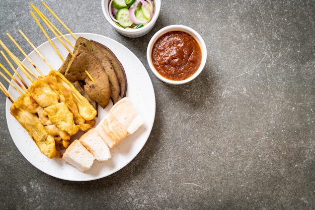 Pork Satay with your Peanut Sauce  and pickles which are cucumber slices and onions in vinegar