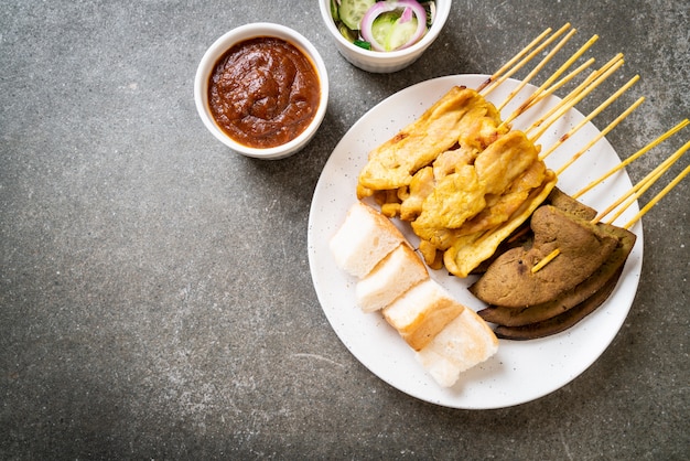 Pork Satay with your Peanut Sauce  and pickles which are cucumber slices and onions in vinegar