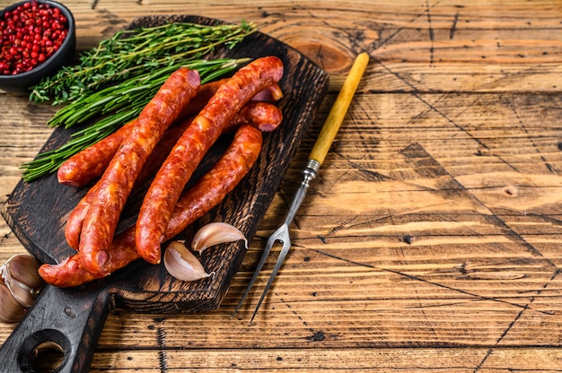 Pork Smoked sausages with addition of fresh aromatic herbs and spices. wooden background. Top view. Copy space.