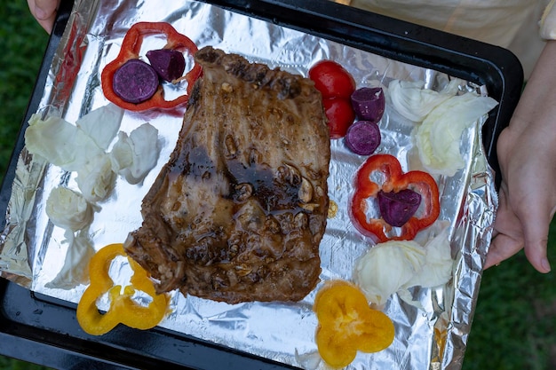 Pork spare ribs on black tray with vegetables.