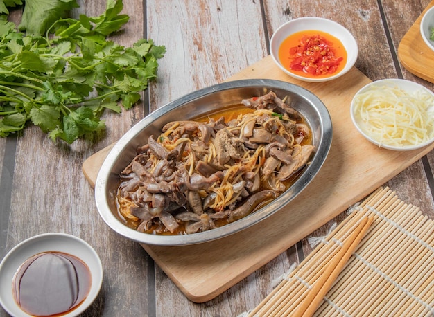 Pork and squid noodles water with chilli sauce noodles spoon and chopsticks served in dish isolated on napkin top view of hong kong food