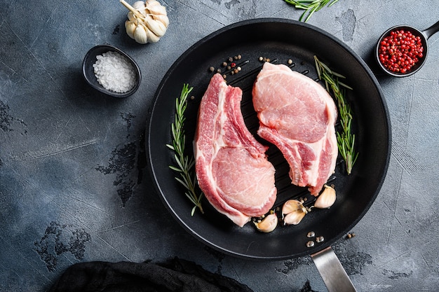 Pork steaks, fillets for grilling, baking in frying pan black skillet with herbs, spices top view flatlay .