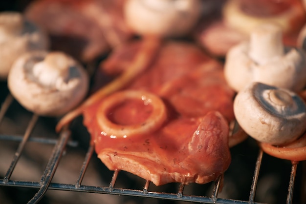 Pork in tomato sauce with onion rings and mushrooms cooking outdoors on the grill outdoor barbecue