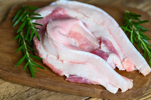 Pork on wooden plate with rosemary fresh raw streaky pork meat for cooking food pork skin pig skin top view