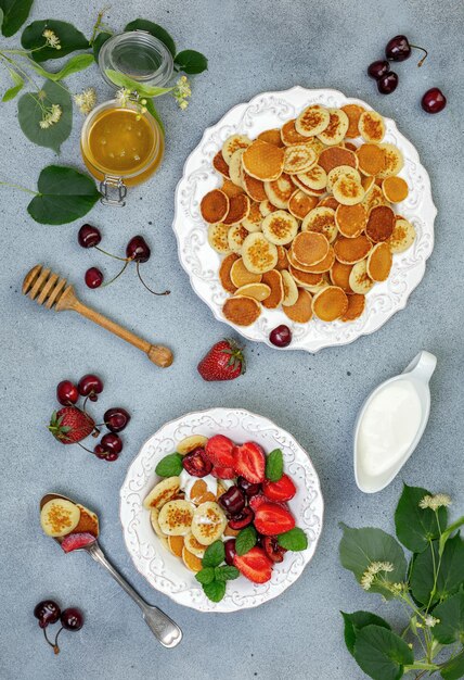 Photo porridge of tiny pancakes with berries cream and honey