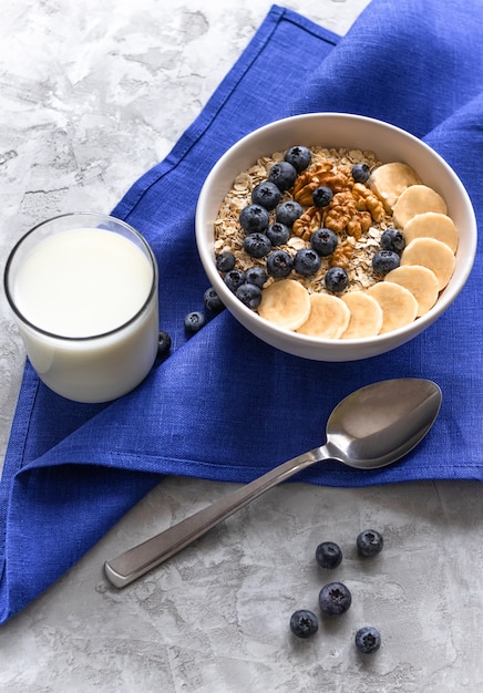 Porridge with bananas, blueberries and walnut and glass  of milk for healthy breakfast or lunch.