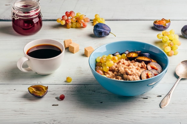 Porridge with fresh plum green grapes and cup of coffee