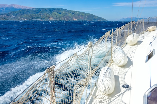 The port of a sailing yacht with a guard rail and fenders. Deep blue sea and sea foam