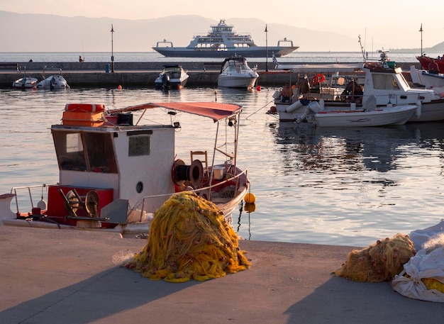 Port with ferryboat and fishing boats at sunset on Greek island of Evia in Greece