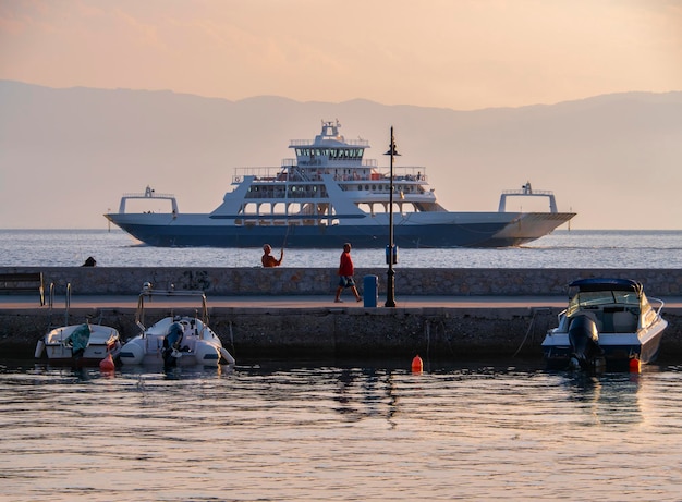 Port with ferryboat and fishing boats at sunset on Greek island of Evia in Greece