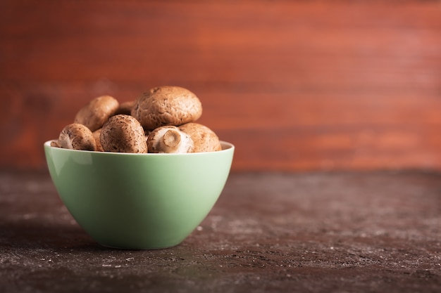 Portabello mushrooms in a green bowl on a dark background