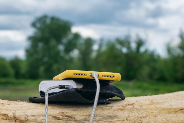 A portable charger charges the smartphone Power Bank with cable against the background of wood