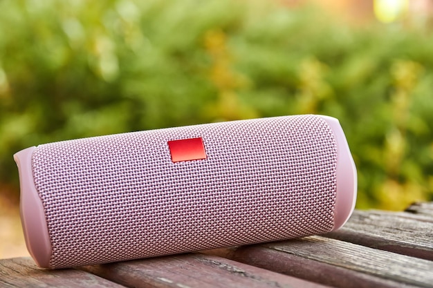 Portable pink wireless speaker in the city on a wooden surface