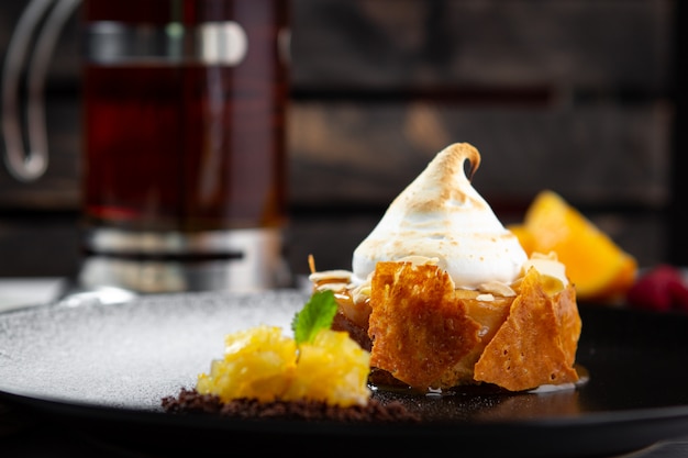 A portion of Apple pie with cream on a black plate