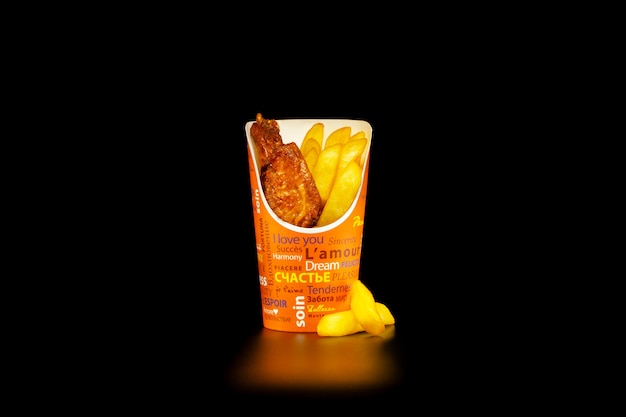 A portion of chicken wings barbecue with French fries in a cardboard Cup 