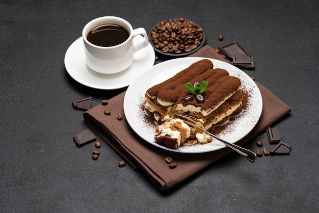 Portion of Classic tiramisu dessert and cup of fresh espresso coffee on concrete background or table