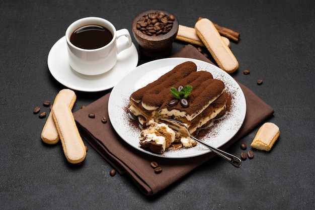 Portion of Classic tiramisu dessert and cup of fresh espresso coffee on concrete background or table