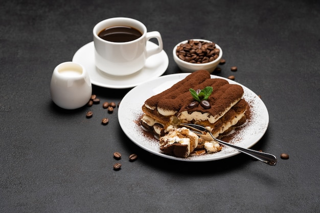 Portion of Classic tiramisu dessert and cup of fresh espresso coffee on concrete background or table