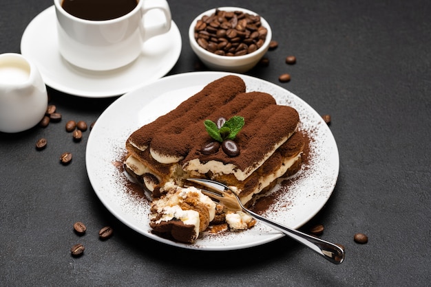 Portion of Classic tiramisu dessert and cup of fresh espresso coffee on concrete background or table