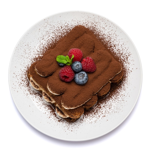 Portion of classic tiramisu dessert with berries on a ceramic plate