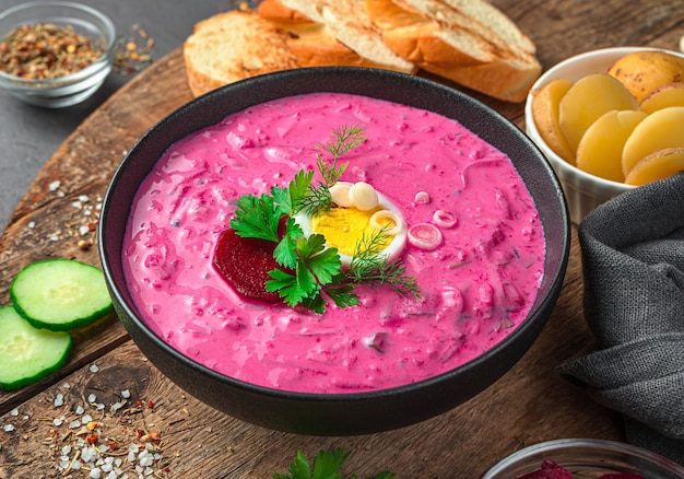 A portion of cold beetroot soup with herbs, egg and cucumber. Side view, close-up. A traditional Lithuanian dish.