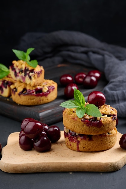 Portion crumble pie with cherries on a wooden board decorated with green mint leaves