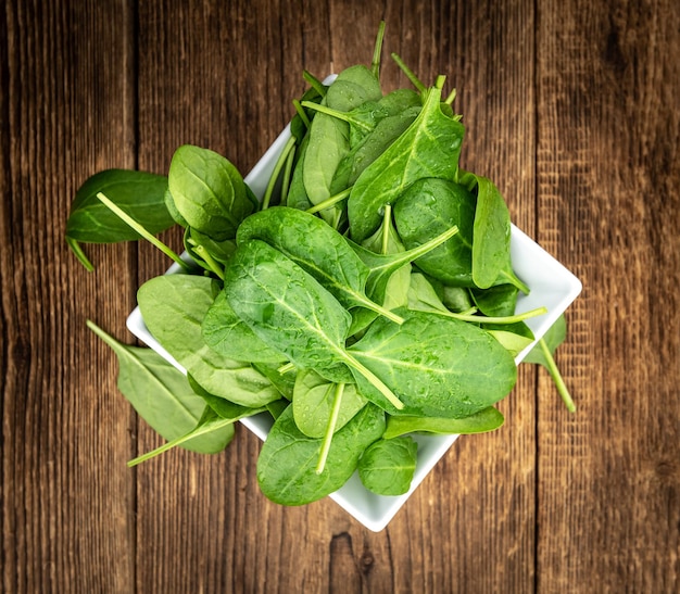 Portion of fresh Spinach on a wooden table closeup shot