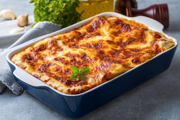 Portion of ground beef lasagna topped with melted cheese and garnished with fresh parsley served on a plate in close view for a menu