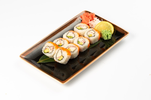 A portion of maki sushi with an assortment of Japanese side dishes in a rectangular ceramic plate on a white background