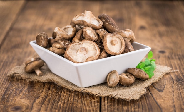 Portion of Raw Shiitake mushrooms on wooden background selective focus