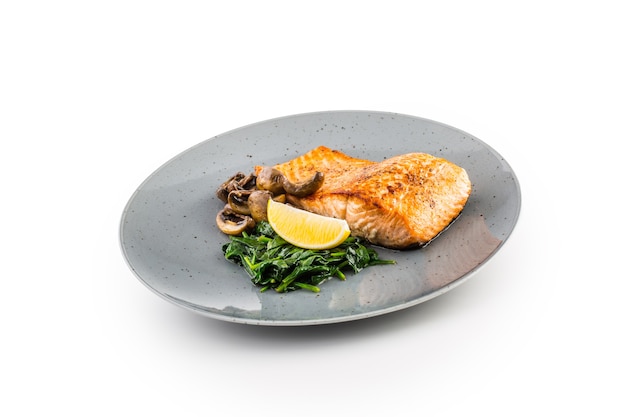 Portion of roast salmon fillet with spinach mushrooms isolated on white background