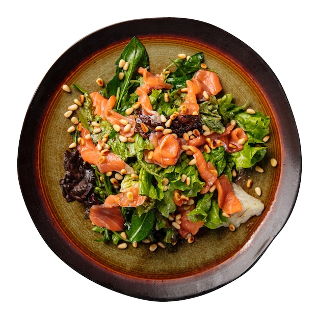 Portion of salmon salad with greens and pine nuts