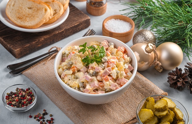 A portion of traditional Russian salad olivier on a light background. Side view, horizontal.