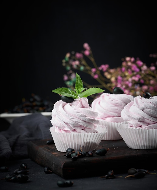 Portioned fruit marshmallows in a paper cup on a black wooden board delicious dessert