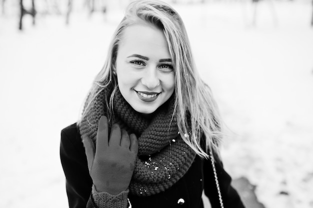 Portrai of blonde girl in red scarf and coat on winter day.