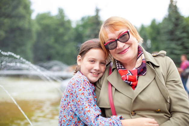 Portrait of 65yearold woman with granddaughter on background of fountain in park