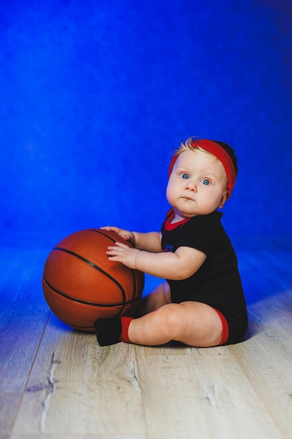 Portrait of a 7monthold baby in a black bodysuit with a basketball Sports for kids Cotton clothes for babies