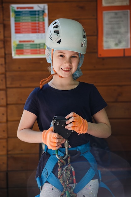 Portrait of 8 years old girl in forest adventure park. Outdoor playground with rope way.