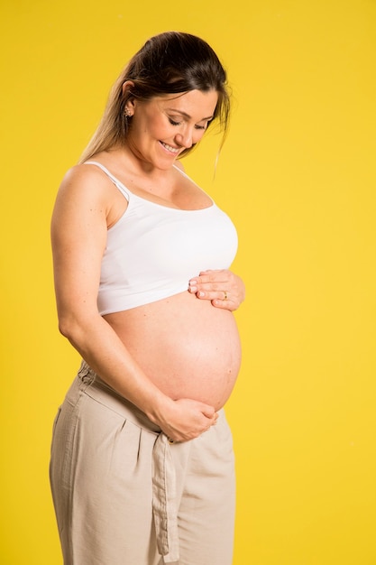 Portrait of 9 months pregnant woman over yellow wall