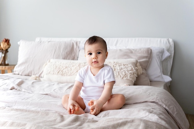 Portrait of a 9monthold girl with brown eyes sitting on a bed