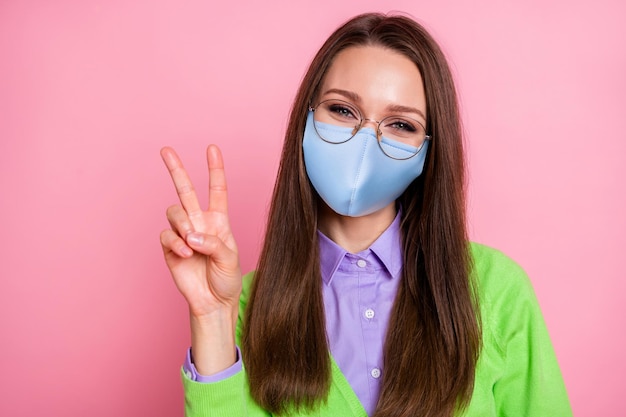 Portrait of adorable charming youth girl  make v-sign wear respiratory mask isolated over pastel color background