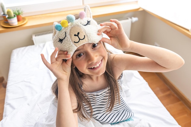 Portrait of adorable little girl walked up in her bed in the sunny morning